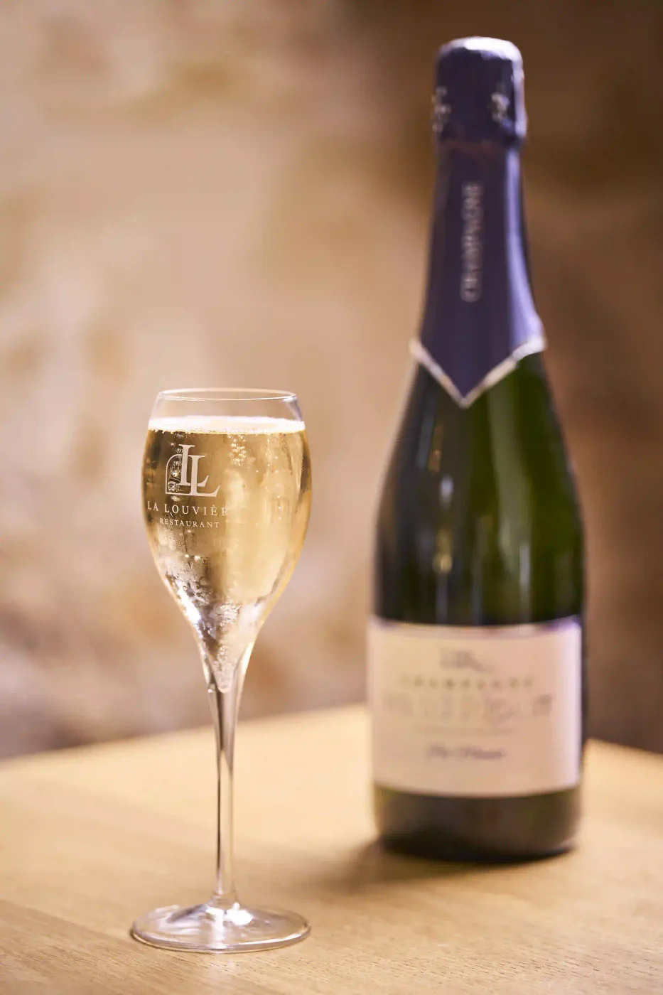 Flûtes de champagne et bouteille au logo du restaurant La Louvière à Septmonts